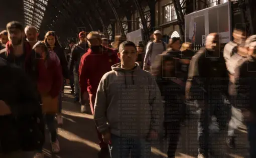 People walk down the street. Digital squares are placed over the face of each person, presumably to identify individual facial features.