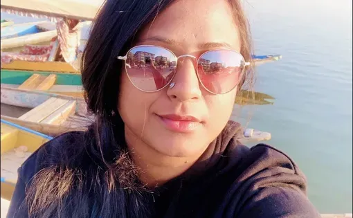 A woman with long hair wearing sunglasses and a dark sweatshirt