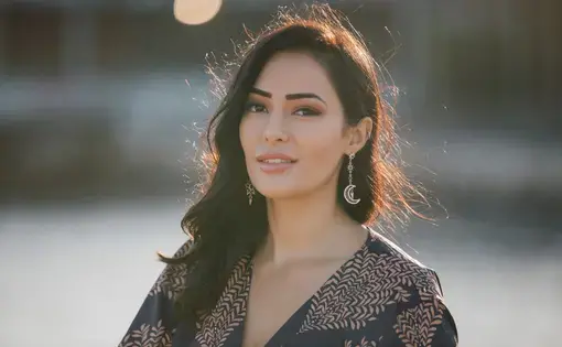 A woman with long dark hair wearing drop earrings and a black blouse