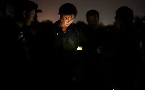 A flashlight illuminates the face of a man.