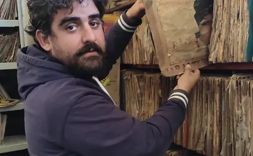 Cesar is putting an old book back into the shelf.