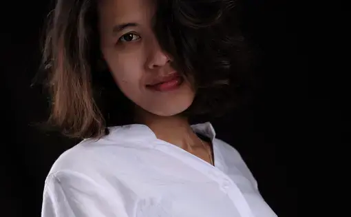 Choulay poses in a stark white shirt against a black backdrop.
