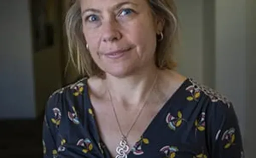 A woman with blonde hair wearing a navy printed dress