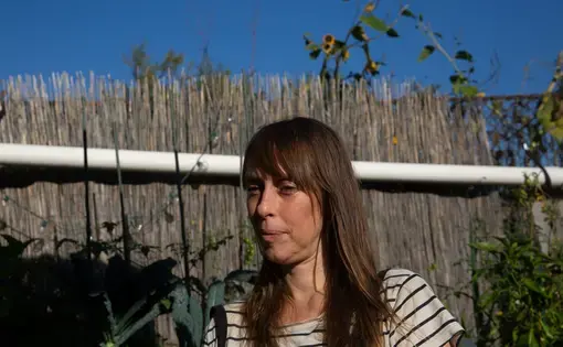 A woman stands next to a fence