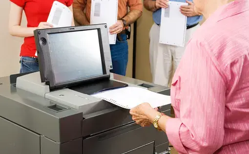 Closeup of a woman feeding her ballot into Florida's new optical scanner machine. Image by Lisa F. Young/Shutterstock