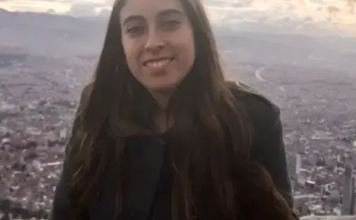 Isbale smiles at the camera against a stunning view of a city.