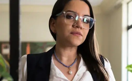 Thalíe Ponce wears glasses and a white button down shirt