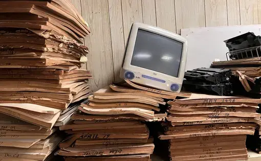 An old iMac sits atop newspapers.