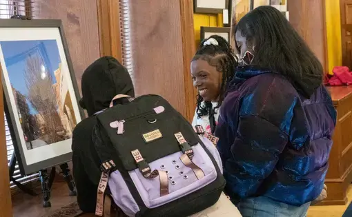 Three students look at a framed photo in the Everyday Dc exhibition