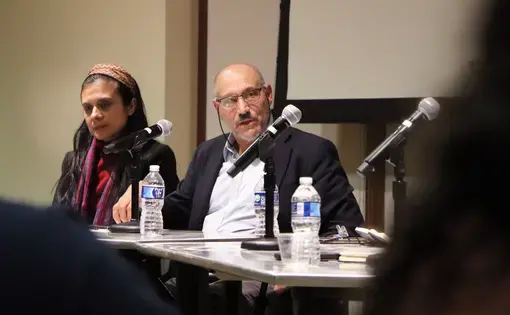 A man speaks at a panel table with microphones