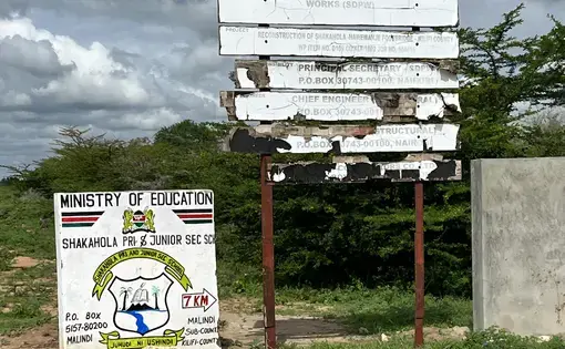 A run down sign with a forest in the background