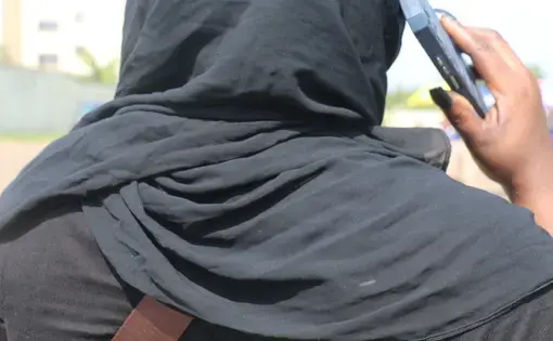 picture taken from behind, cropped in close, of a veiled woman talking on a cellphone