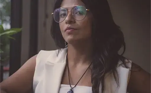Headshot of Jessica wearing glasses and a white vest