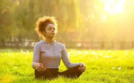 Young African American woman meditating in nature. Image by mimagephotography/Shutterstock.