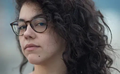 Headshot of Camille wearing glasses and an orange shirt