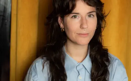 Molly wearing a blue button down against a yellow background