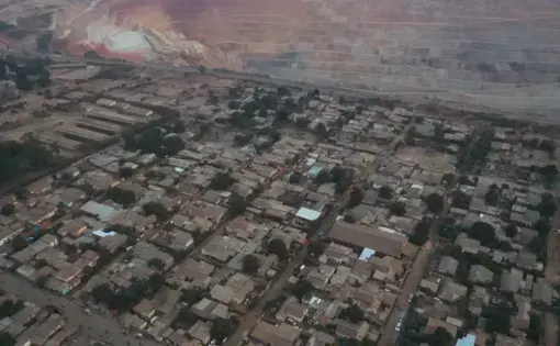 Aerial view of a town, where on the edge of the frame a huge mine pit has been dug into the earth.