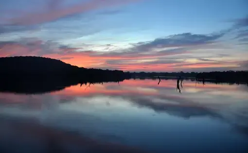 a pink and blue sunset reflects on a lake
