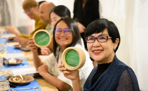 Dinner attendees present the messages found at the bottom of their steam basket plates.