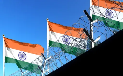 Orange, white, and green flags behind barbed wire