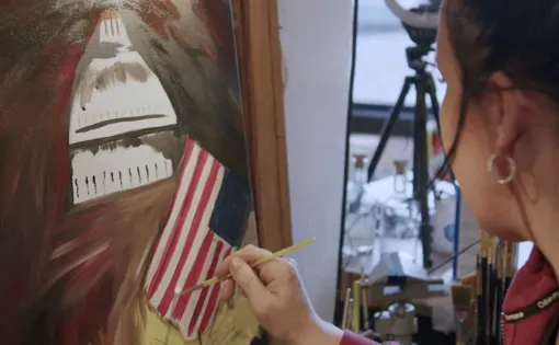 a woman paints the U.S. Capitol and American flag