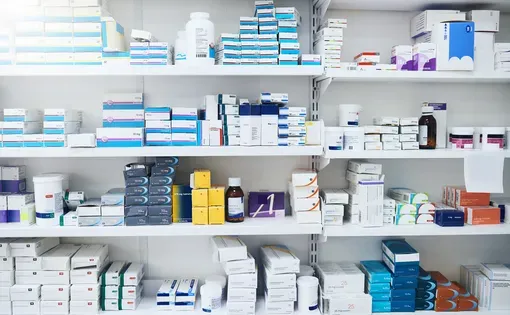 Pharmacy shelves stacked with bottles and boxes of medications