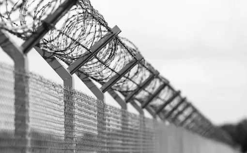 Barbed wire lines the top of a chain-link fence