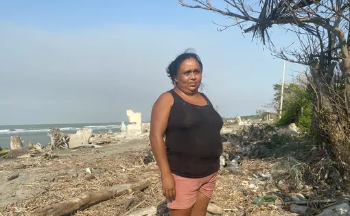 A woman in a black top stands in a beach area