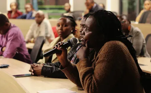 a woman speaks in a microphone at a townhall event