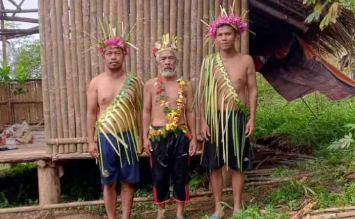 Three men stand for a portrait. They wear knee length pants and head adornments.