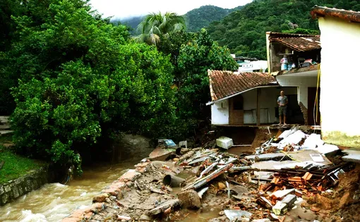 Rio de Janeiro, Brazil April 09, 2019 a man observes the debris of their house in Rio de Janeiro where 10 people dead on April 08 and 09 due to strong rains. Image by Antonio Scorza/Shutterstock.