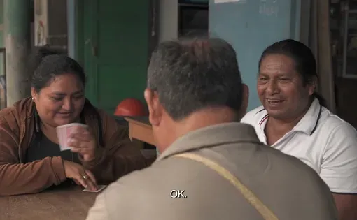 Three people sit at a table together, some laughing at the conversation.