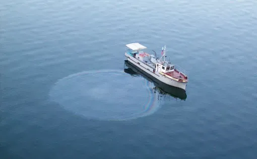 Oil sits atop the water as it leaks from a boat.