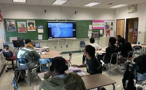 High school students seated in a classroom participate in a virtual journalist visit.