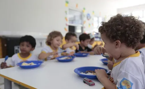 Small children eat around a table.