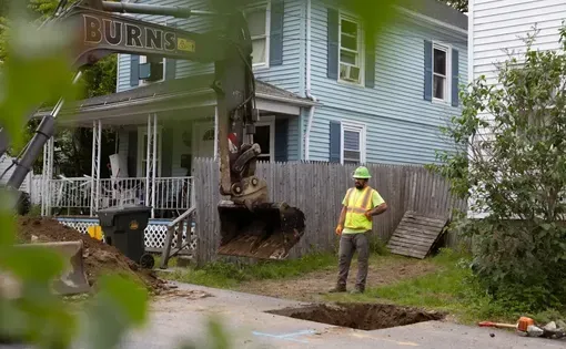 A construction worker surveils the extraction of an old lead line on a New London residential street