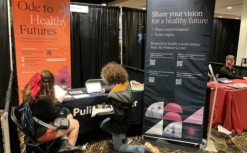Students sit in front of a table at the JEA/NSPA trade show and write poems.