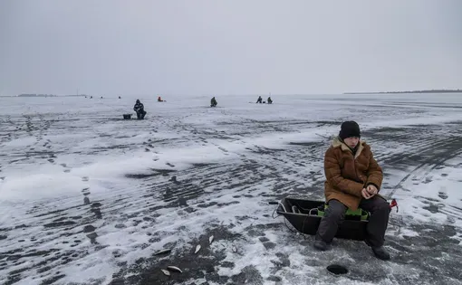 A man fishes in a snowy environment.
