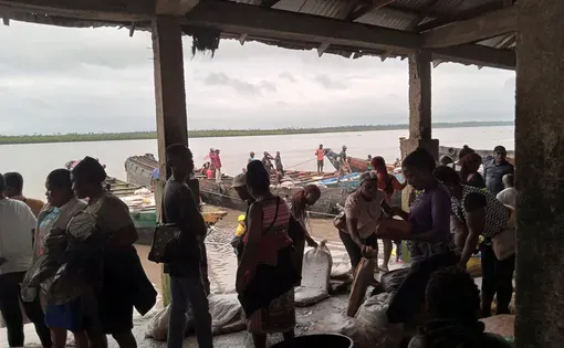 People stand near a boat in Nigeria