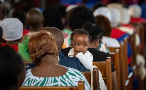 A baby and others sit in a church.