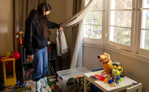 Adriana Valdez pulls back a drape to inspect the layer of ash coating her son’s toys at her home in Altadena on April 1.