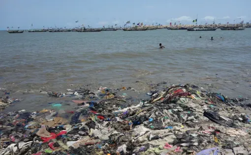 A surplus of secondhand clothes end up littering and contaminating Ghana's beaches and waters. Image by Anne Whiting. 2023.