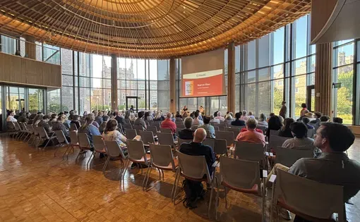 people gather in a large conference room to attend a panel