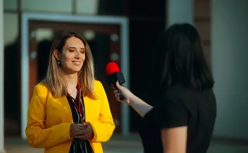 Reporter Interviewing a Young Female Politician Outdoors. Businesswoman being interviews on the street by a journalist