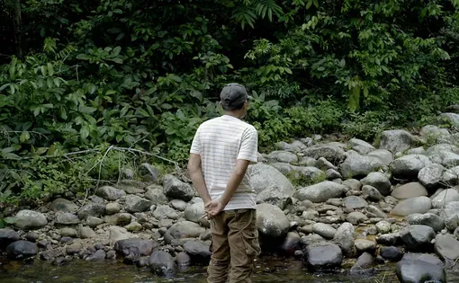 Khairunnas berdiri di atas batu di Sungai Batang Buat, yang dulu pernah meluap dan merusak kebun serta sawah hingga membuat warga kesulitan — sesuatu yang tak ingin mereka alami lagi. (Project M/Adi Renaldi)