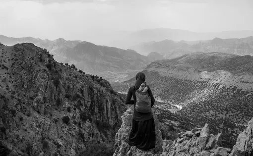 Fereshteh, 14, is photographed in the central Zagros Mountains, where her tribe spends spring and summer. They travel many hours on rough paths throughout the year, from pasture to pasture—and then there's the yearly 10-hour journey from their summer home to their winter home. She says she does not like the nomadic way of life but feels she has no choice but to accept and endure it. Image by Enayat Asadi/NPR. Iran, 2022.