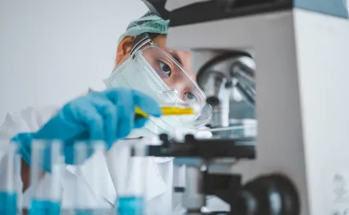 Female researchers are experimenting with pipette dropping a sample into a test tube in an experiment research in laboratory..