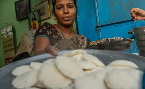 Vimla Selva Satish pulls fresh idlis from the steamer at her Dharavi stall. She says she produces nearly 500 idlis within four to five hours each morning—almost all of which are sold. | Photo Credit: Godson Wilson