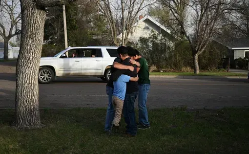 A group of people embraces each other on a neighborhood street.