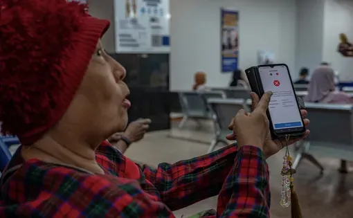 A woman holds a phone showing an app on a screen